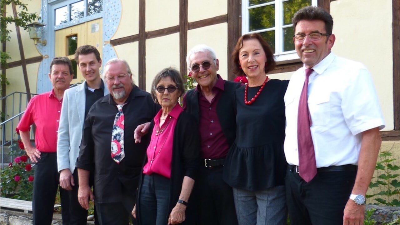 Sieben Musikerinnen und Musiker der Gruppe "Colours of Life" stehen vor einer Hauswand