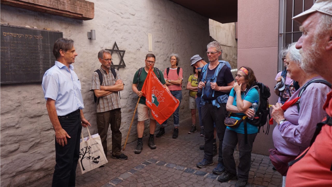Gruppe Menschen hört einem Guide vor einer Gasse in Wertheim zu