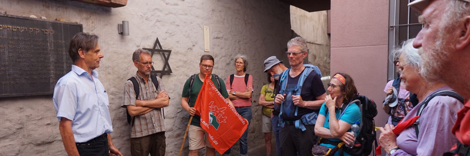 Gruppe Menschen hört einem Guide vor einer Gasse in Wertheim zu