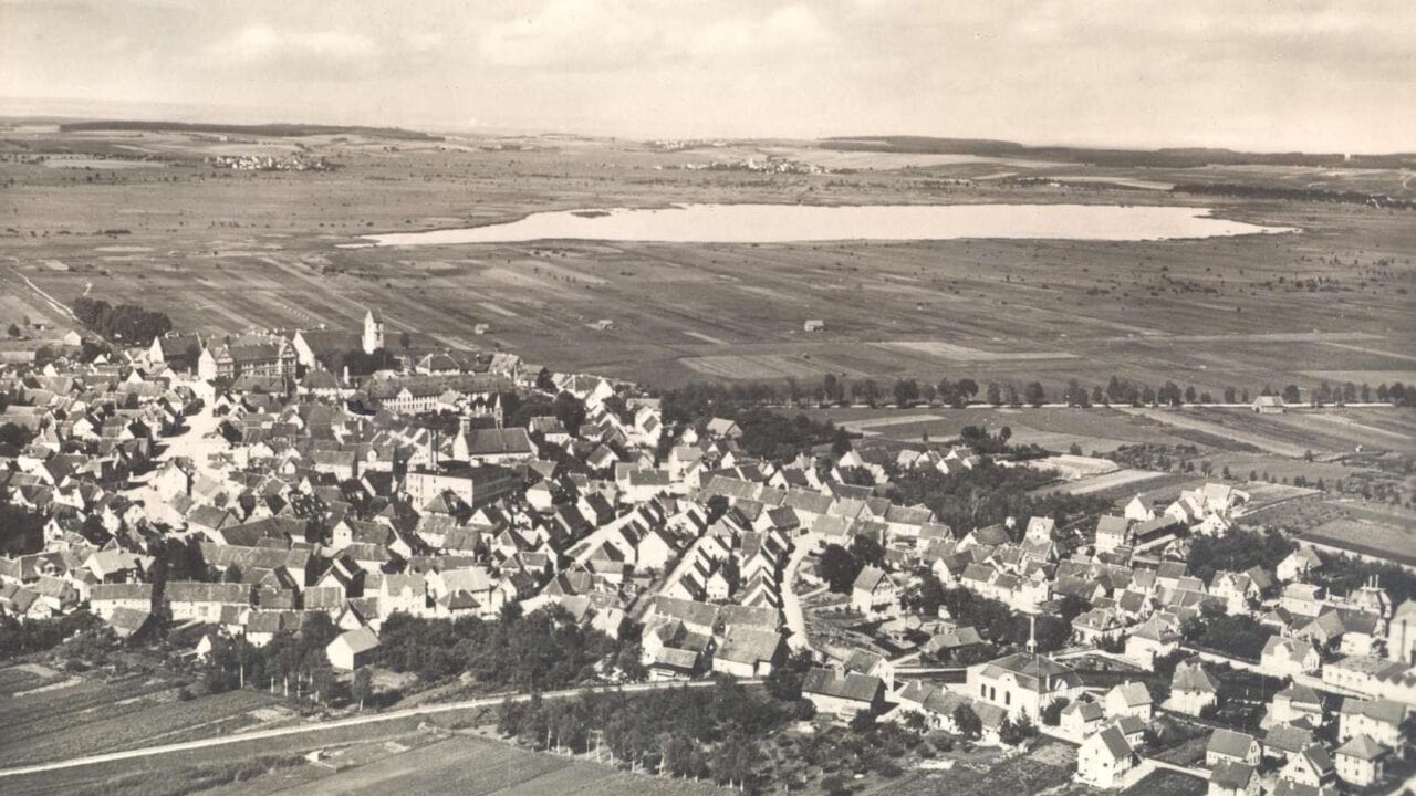 historisches Luftbild in Schwarz-weiß der Stadt Bad Buchau mit Federsee im Hintergrund