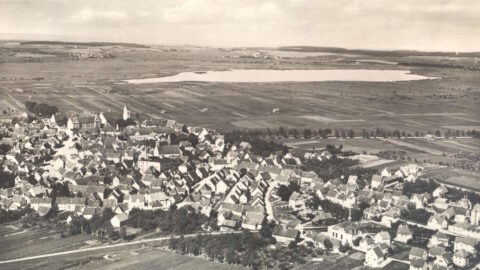 historisches Luftbild in Schwarz-weiß der Stadt Bad Buchau mit Federsee im Hintergrund