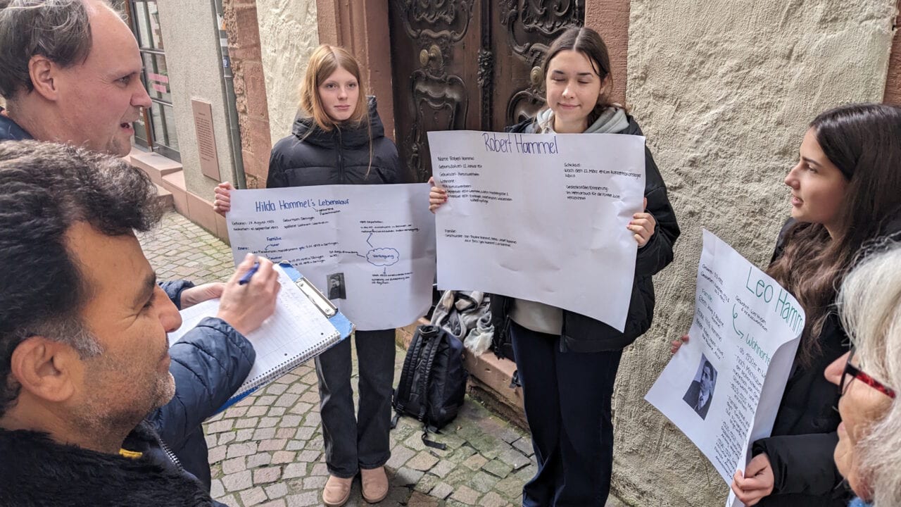 Schülerinnen und Schüler halten Plakate in einer Straße hoch