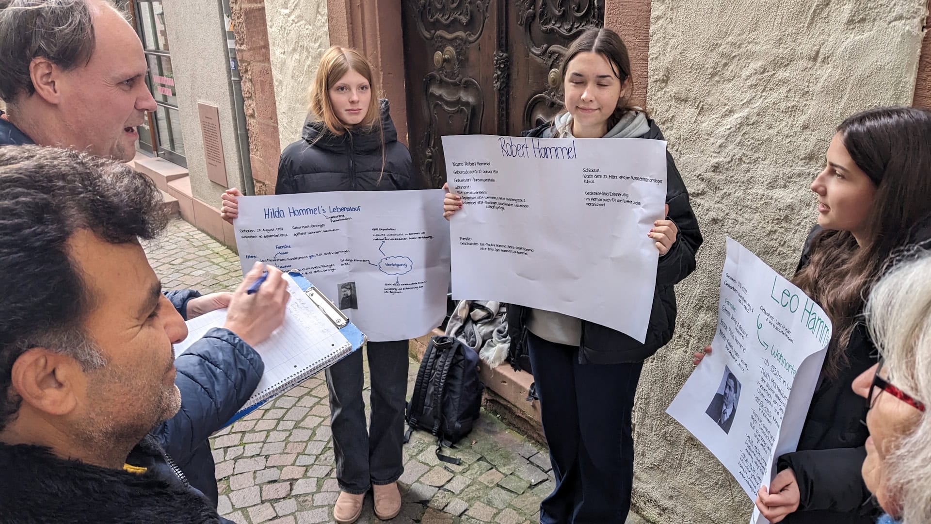 Schülerinnen und Schüler halten Plakate in einer Straße hoch