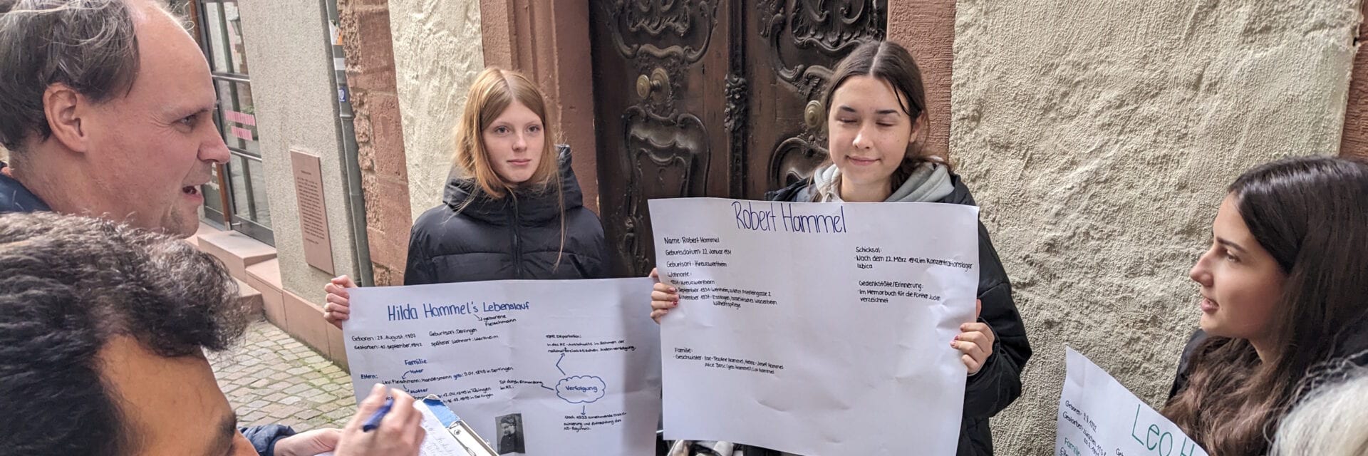 Schülerinnen und Schüler halten Plakate in einer Straße hoch